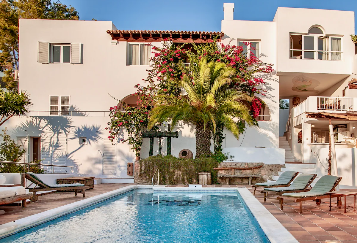 Villa pool with sun loungers and the white facade in warm evening light